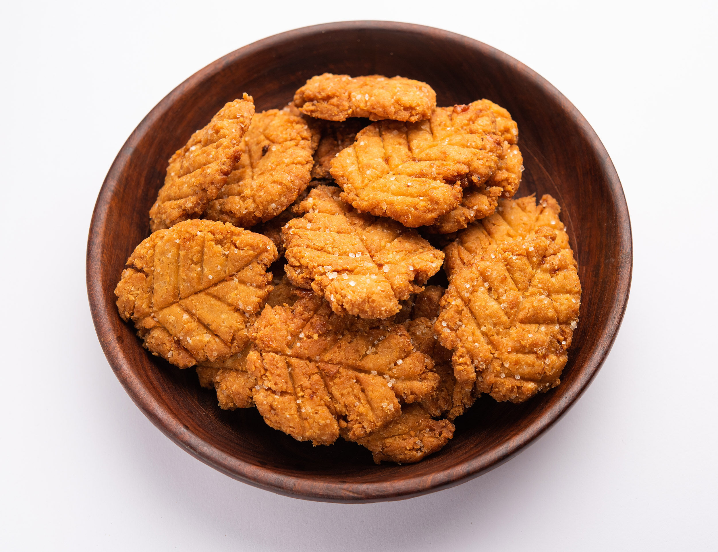 A wooden bowl of Thekua, the essential traditional sweet prasad for the Chhath Puja festival rituals.